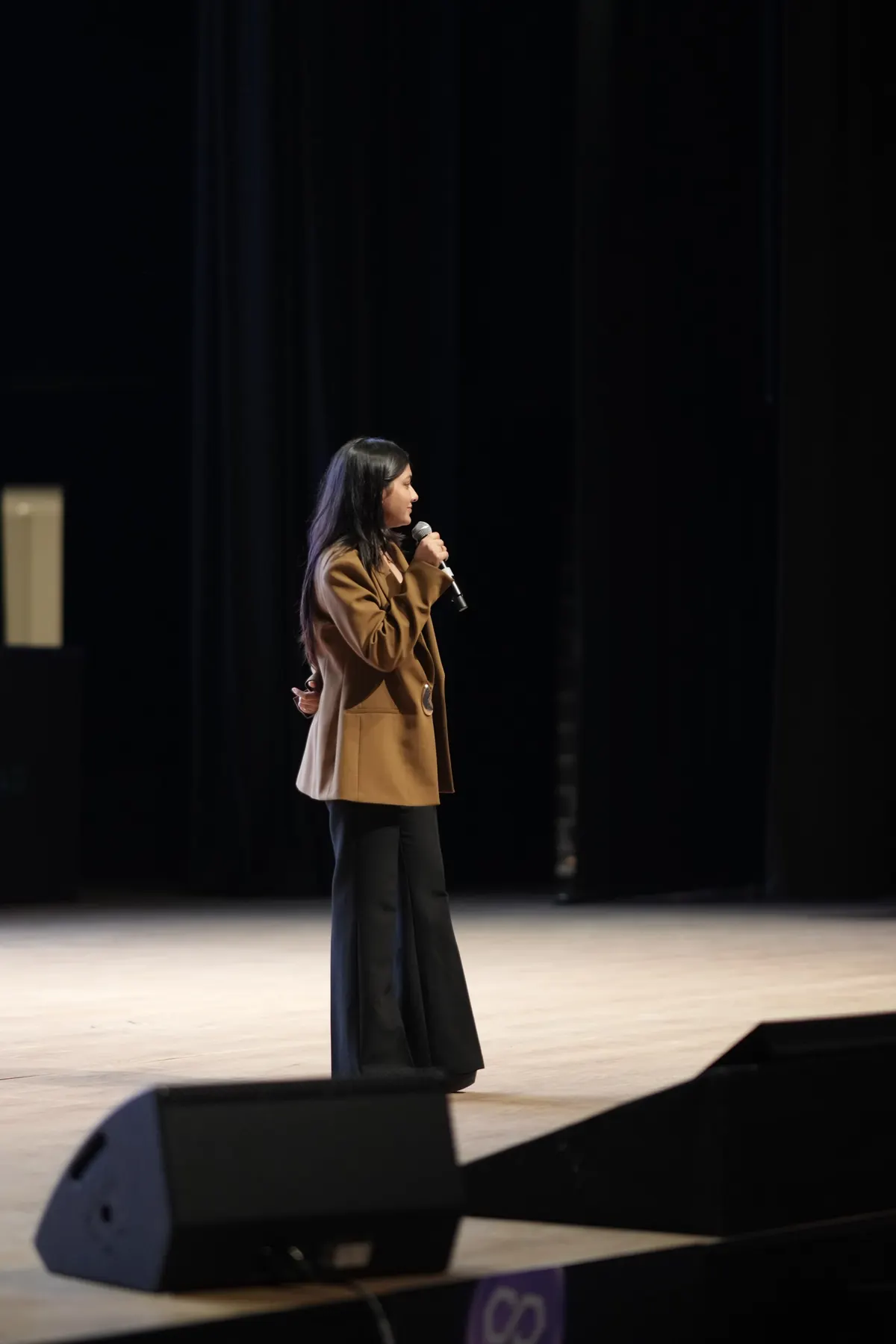 A speaker alone on a wide conference stage
