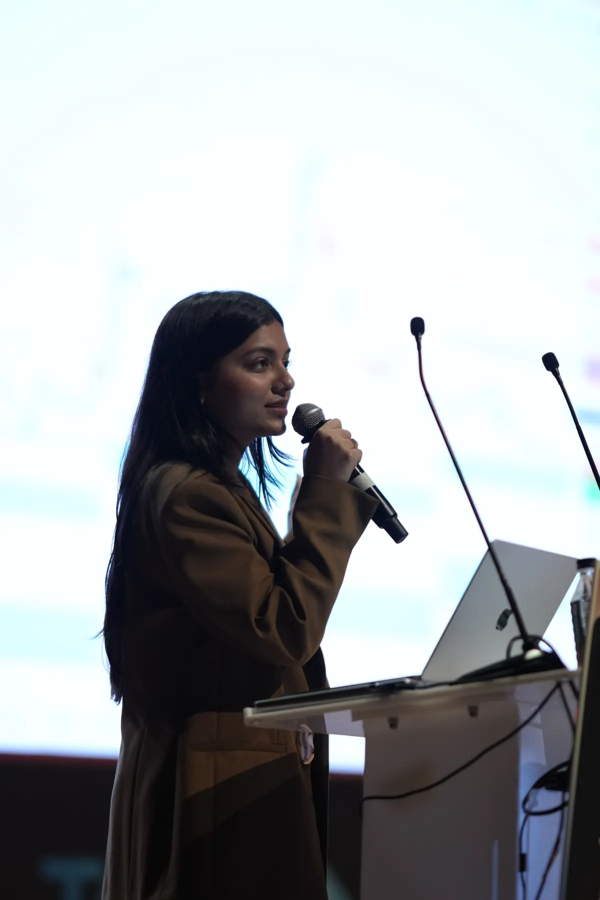 A speaker at the podium with a laptop and microphones