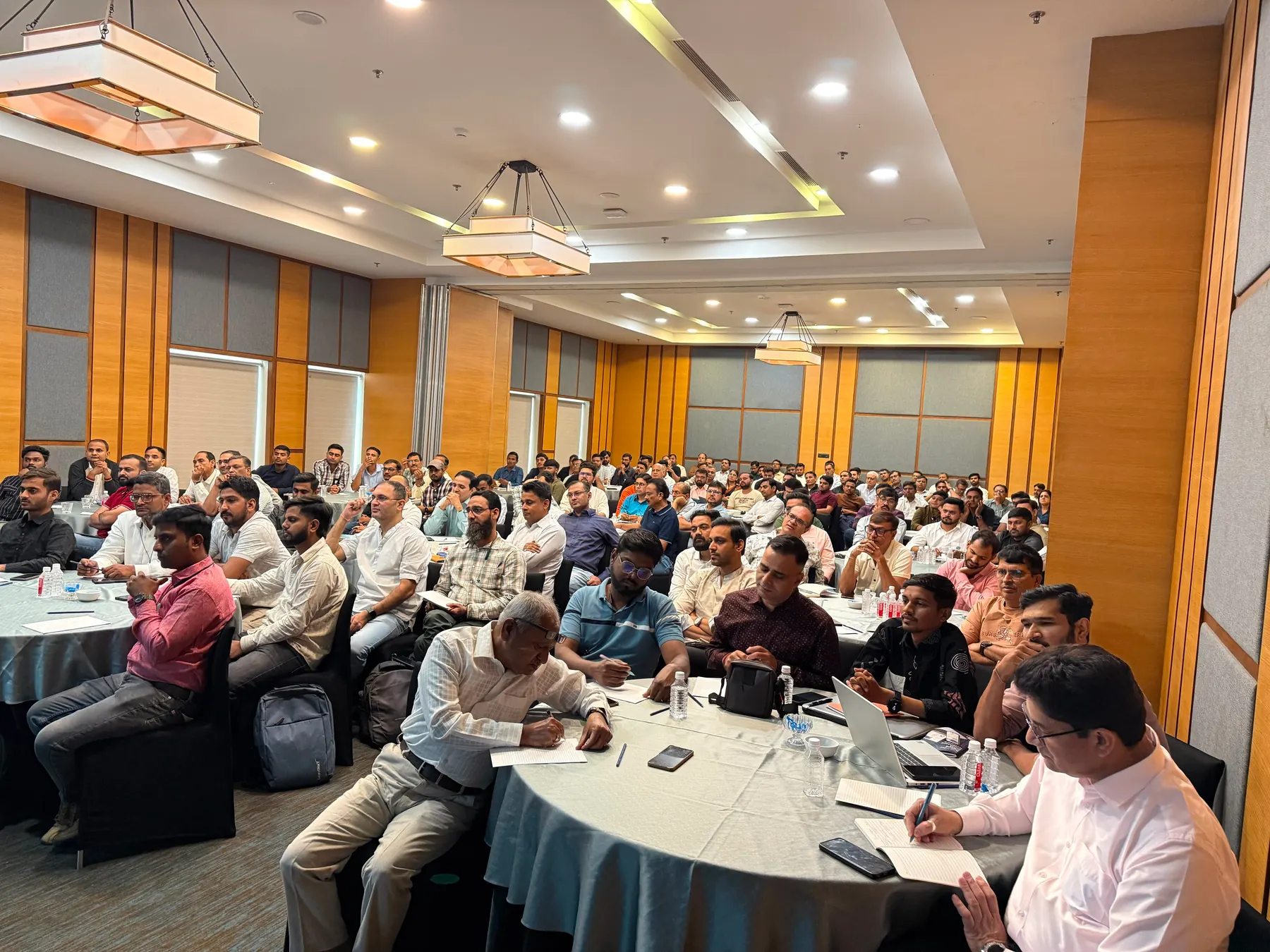 A full room of traders at a workshop, seated around round tables